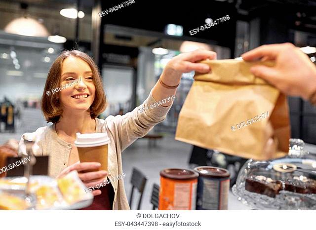 small business, takeaway food, people and service concept - happy female customer with coffee cup taking paper bag from man or barman at vegan cafe