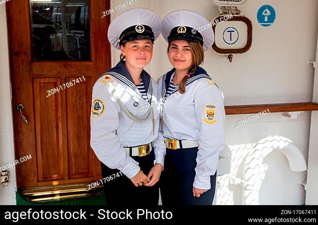 Russia, Vladivostok, 07/28/2018. Portrait of two young beautiful ladies sailors in official marine uniform on the deck of the sailboat