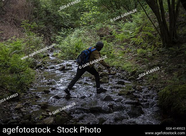 A Sub-Saharan migrant passes a creek while crossing the spanish-french border clandestinely. May 21, 2021. Biriatu (Basque Country)
