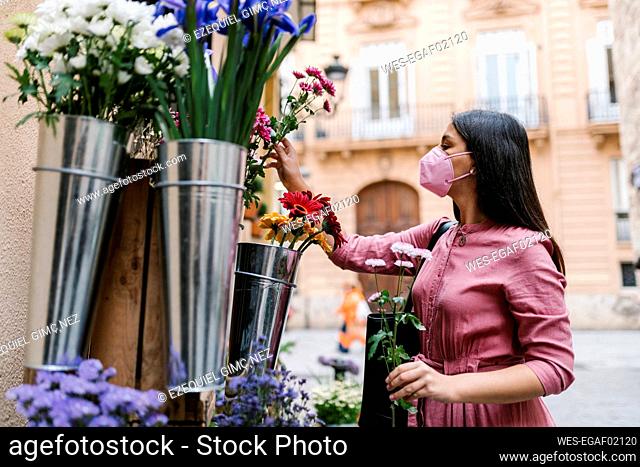 Female customer with face mask looking at flowers displayed