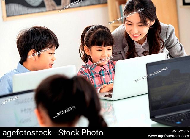 The teacher counseling the children use the computer