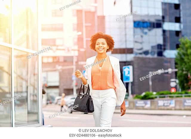 business and people concept - young smiling african american businesswoman in city