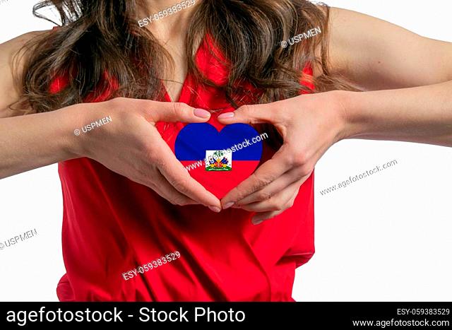 Love Haiti. The woman holds a heart in the form of the flag of Haiti on her chest. Concept of patriotism