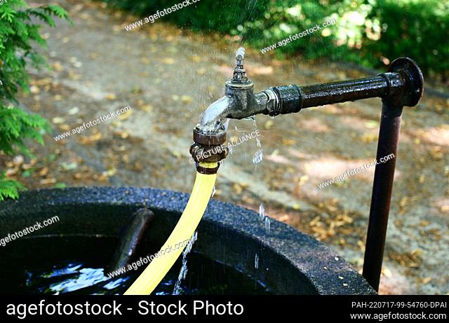 27 June 2022, Berlin: 27.06.2022, Berlin. Drops of water fly from an old outdoor faucet and a leaking garden hose. Photo: Wolfram Steinberg/dpa Photo: Wolfram...