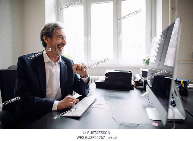 Laughing senior businessman working at desk in office