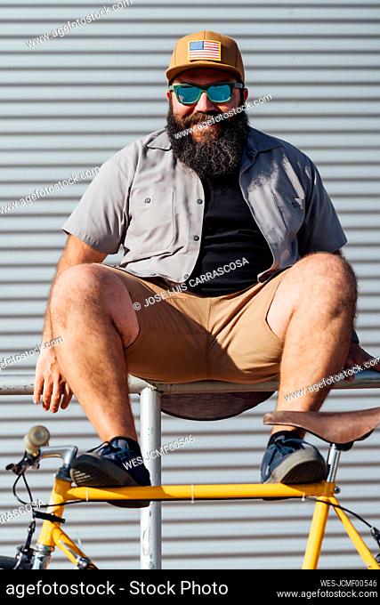 Portrait of bearded man with fixie bike sitting on railing