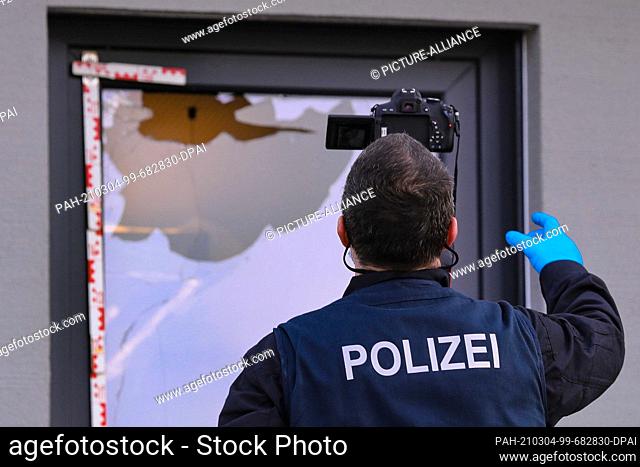 03 March 2021, Saxony, Dresden: Criminal investigator photographs a smashed window at the scene. Photo: Tino Plunert/dpa-Zentralbild/ZB