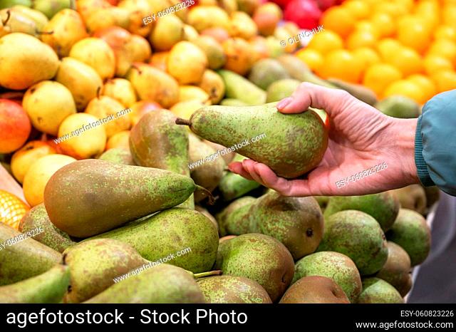 Hands of a woman choosing pear at fruit and vegetable market