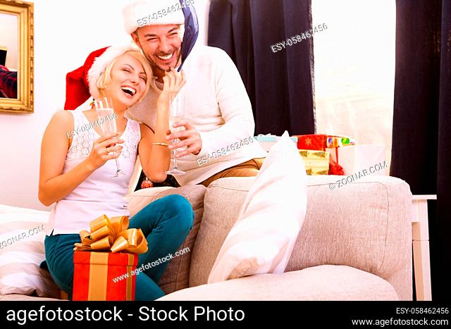 Happy Christmas couple drinking champagne from glasses, smiling and celebrating New Year at home atmosphere. New Year, Christmas, Santa Clause concepts