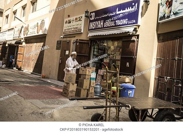 A man with goods in front of a general trading store on the street of Dubai's old district Al Ras, Deira. Nearby is the famous Dubai Spice Souq Market