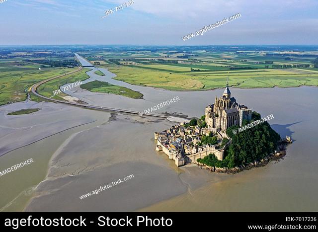 Drone shot from the Atlantic Ocean to the historic monastery of Le Mont Saint Michel, looking into the countryside with the access dam and the Coueson river...