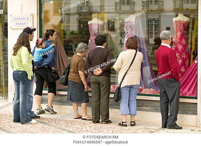 People look at women's dresses in store window in village center of Tomar, Portugal