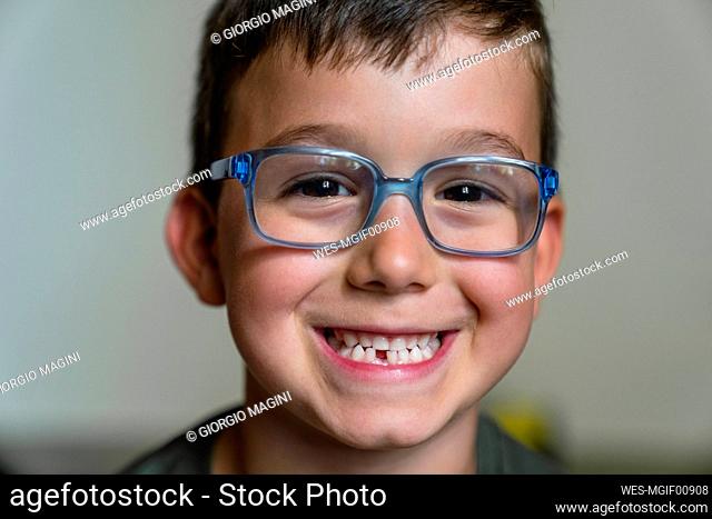 Portrait of little boy with tooth gap wearing blue glasses