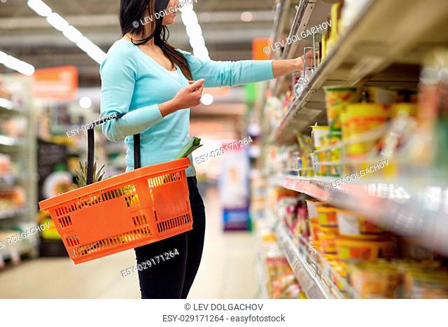 sale, shopping, consumerism and people concept - woman with food basket at grocery store or supermarket