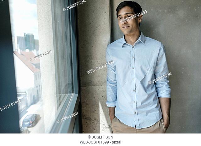 Smiling young man looking out of window