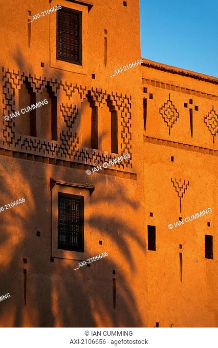 Morocco, Date palm shadow on wall of main kasbah of Dar Ahlam Hotel at dusk; Skoura