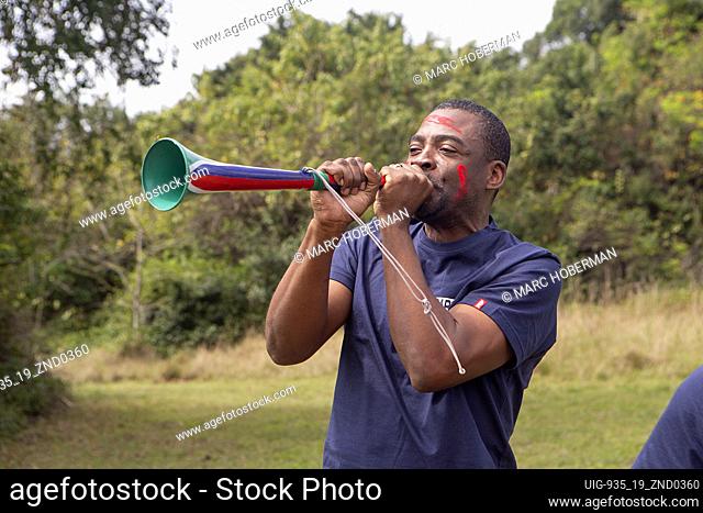 African man playing vuvuzela - a traditional South African instrument