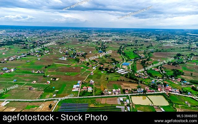 Aerial shot of houses scattered across a large farmland in the countryside Nepal