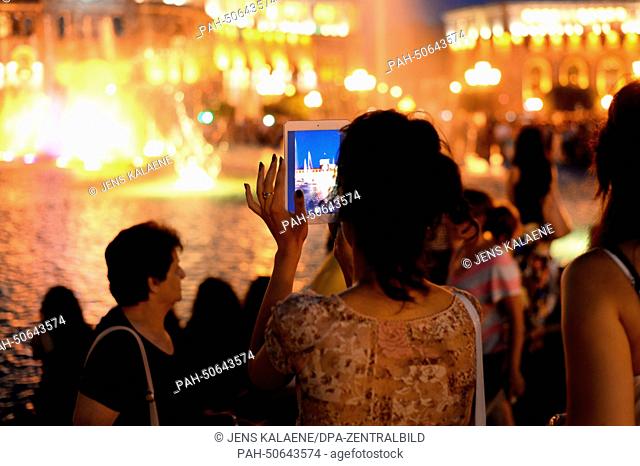 A young woman takes a picture during the evening light show in Yerevan, Armenia, 27 June 2014. Photo: Jens Kalaene/dpa - NO WIRE SERVICE | usage worldwide