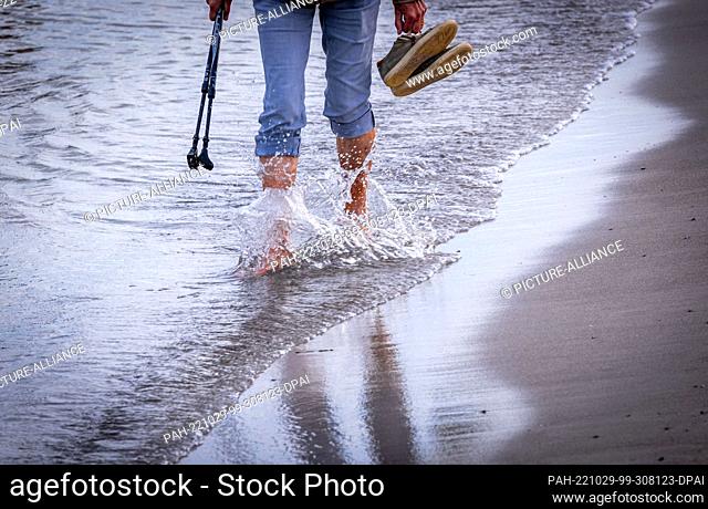 29 October 2022, Mecklenburg-Western Pomerania, Boltenhagen: A vacationer is barefoot during a walk on the beach at the Baltic Sea coast
