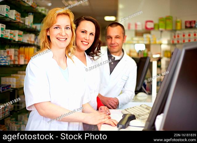 Drei lächelnde Apotheker stehen hinter der Theke