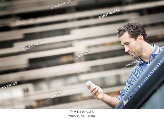 A man standing on a street checking his smart phone