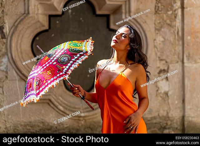 A gorgeous Hispanic Brunette model poses outdoors in home environment holding a parasol