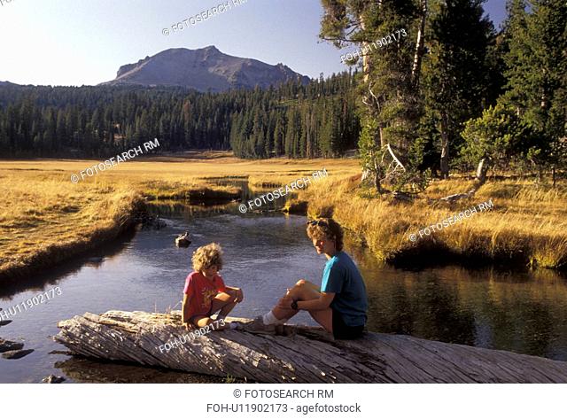 Lassen Volcanic National Park, Lassen, California, Cascade Mountains, Cascade Range, Mother and daughter (7 years old) sit on a log on Kings Creek in Lassen...