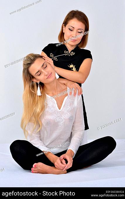 Thai Massage. Massage therapist working with patient, massaging her body on a bed. Studio shooting
