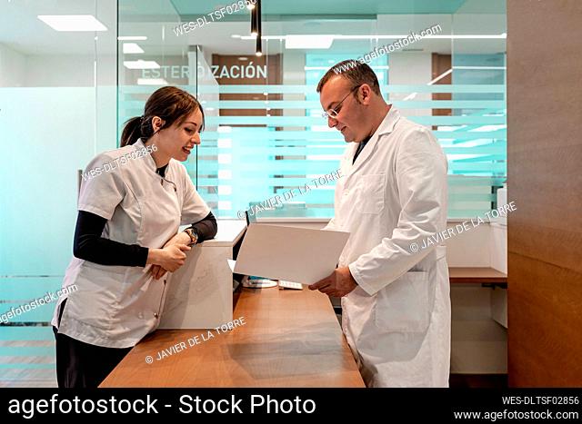 Doctor and nurse discussing on medical record at reception desk in hospital