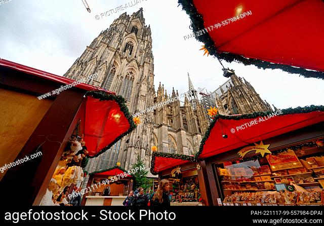 17 November 2022, North Rhine-Westphalia, Cologne: The first visitors walk through the Christmas market in front of Cologne Cathedral