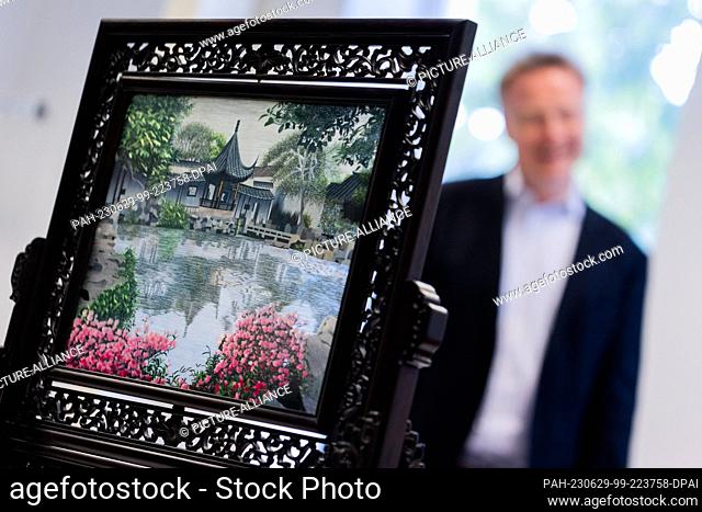 PRODUCTION - 26 June 2023, North Rhine-Westphalia, Duesseldorf: A guest gift from China, an elaborate embroidered picture ""Landscape by the water with pink...