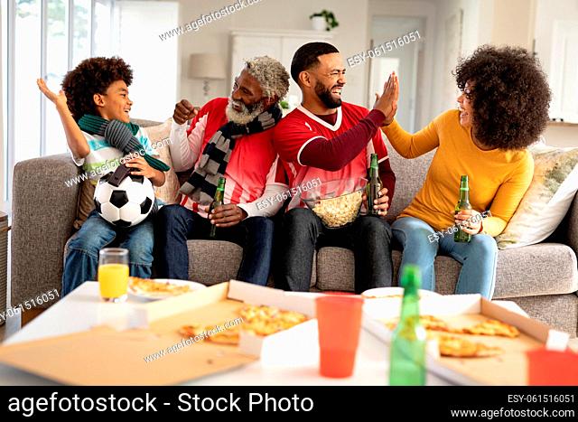 Multi generation family high fiving each other while watching sports on TV