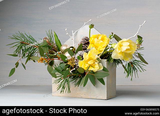 decorative bouquet in a wooden box. of yellow flowers and fir branches. on a light background