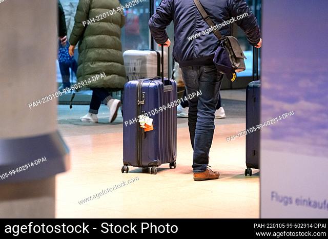 04 January 2022, Hamburg: Returning passengers of the cruise ship ""Aidanova"" walk through the arrivals area of Hamburg airport with their suitcases during the...