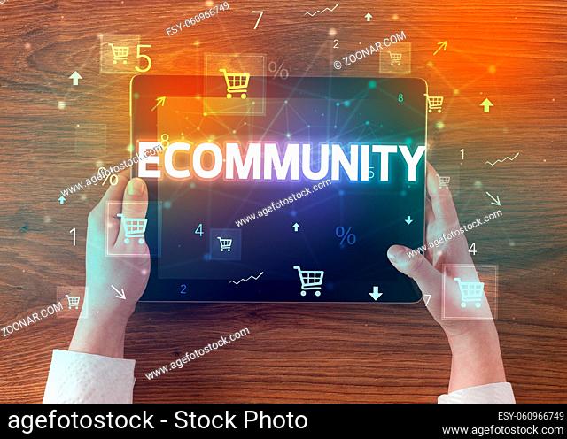 Close-up of a hand holding tablet with ECOMMUNITY inscription, online shopping concept