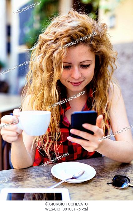 Woman at outdoor cafe looking at cell phone