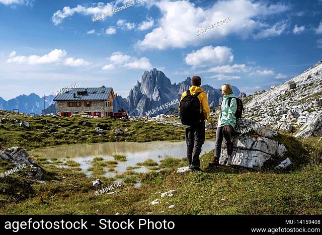 couple in dolomites. rifugio lavaredo with cadini di misurina mountain group in background. italy