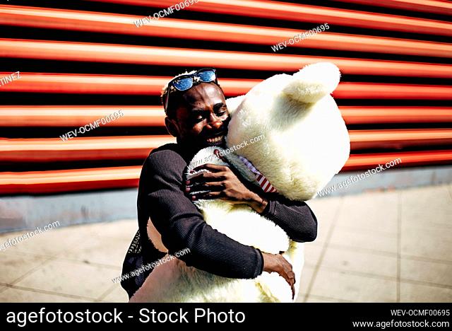Happy young man hugging huge teddy bear