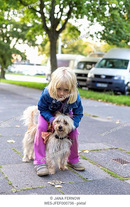 Little girl standing on pavement with her mongrel