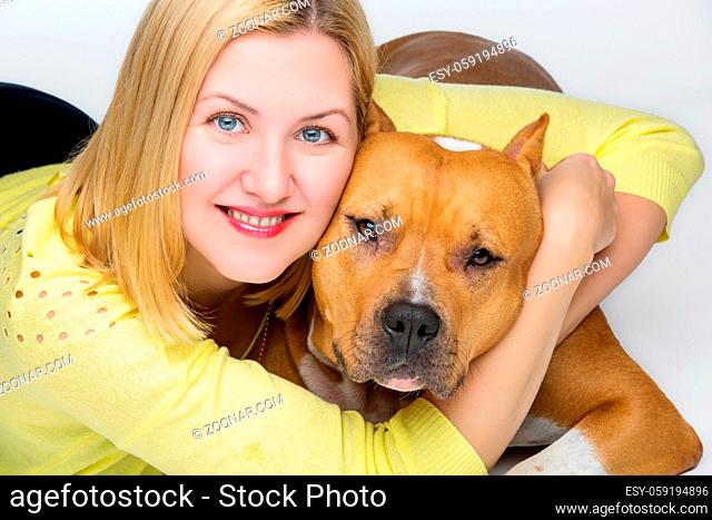 Beautiful happy young woman hugging american staffordshire terrier dog. Studio shot isolated on white background. Copy space