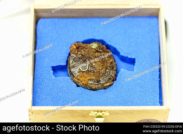 20 March 2023, Rhineland-Palatinate, Mainz: A fibula (7th century AD, found at Bösfeld, near Mannheim) embedded in soil lies in a box