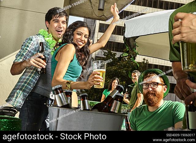 Friends dancing and drinking beer on outdoor patio while watching St Patrick's Day parade