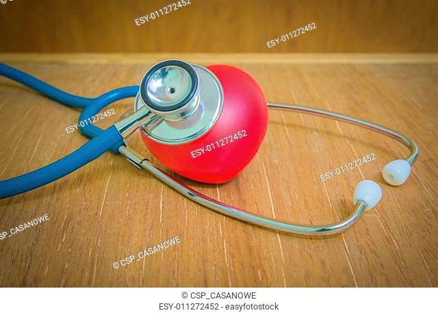 Red heart and stethoscope on wooden background