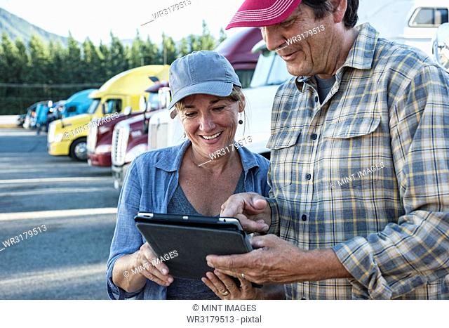 Caucasian woman and man truck driving team working on their driving log in a truck stop parking lot
