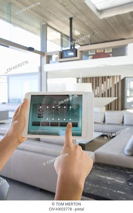 Personal perspective woman with digital tablet setting digital climate control in modern, luxury home showcase interior living room