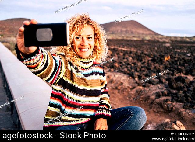 Portrait of woman wearing colorful pullover and taking a selfie, Tenerife, Spain