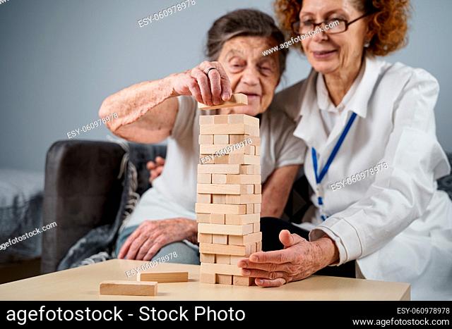 Mature doctor conducting session, therapy for senior patient in nursing home, training fine motor skills for dementia, alzheimer disease and recovery institute...