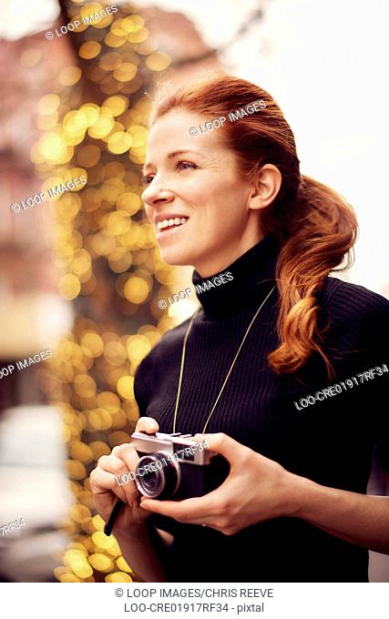 Young fashionable women with classic camera in front of lights in New York city