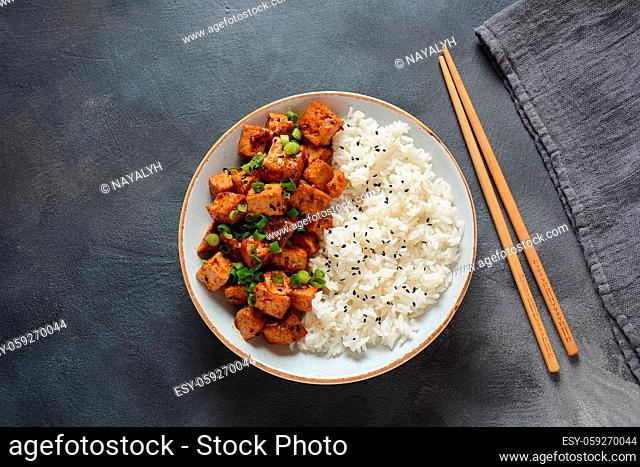 Sweet, spicy , crispy and fried Tofu in teriyaki sauce served in a bowl with sesame seeds and rice. Healthy vegan food, gluten-free